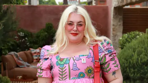 Getty Images Blonde woman wearing pink sunglasses and a pink dress 