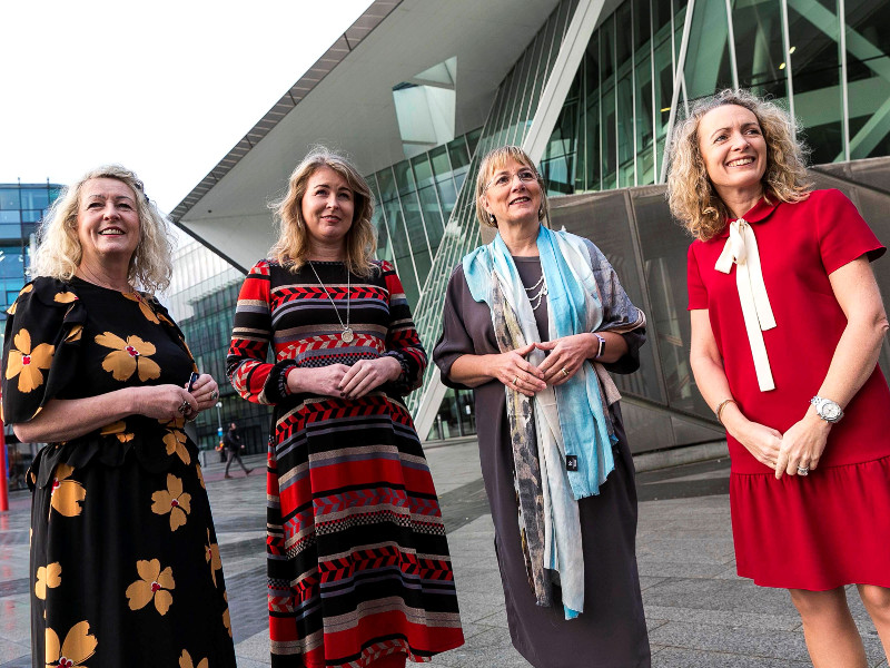 four women in colourful dresses.